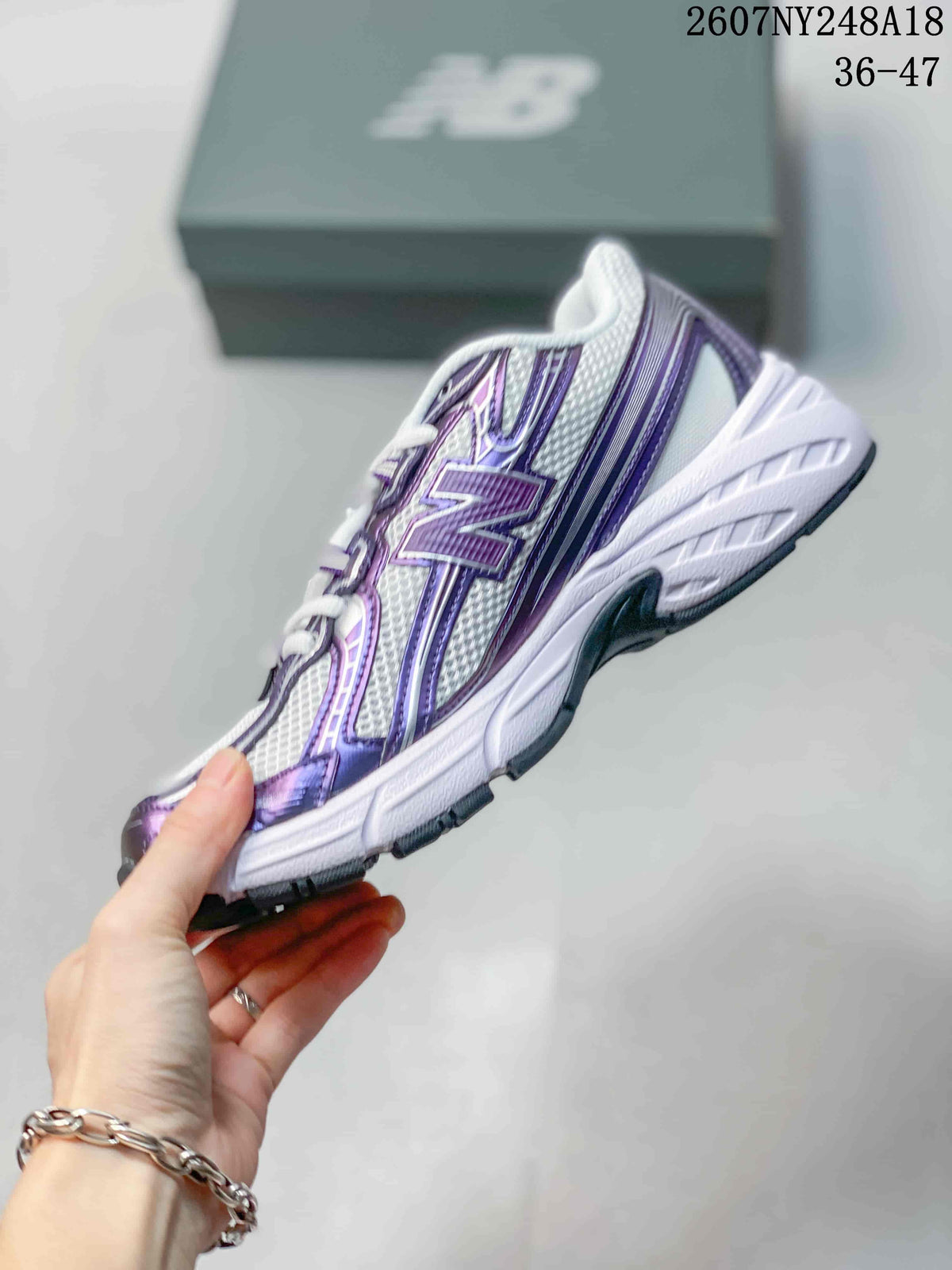 Side profile of a white and purple New Balance 740 sneaker with layered panels and a contrasting outsole.