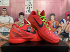 Pair of red basketball shoes shown from the side, with black Swooshes and green laces.