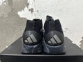 Rear view of black and grey Adidas high-top basketball shoes with three-stripe heel details and marbled grey soles.