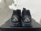 Rear view of black and grey Adidas high-top basketball shoes with three-stripe heel details and marbled grey soles.