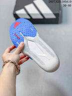 Underside view of the sneaker showing a blue textured outsole, red outsole detail, and central support structure.