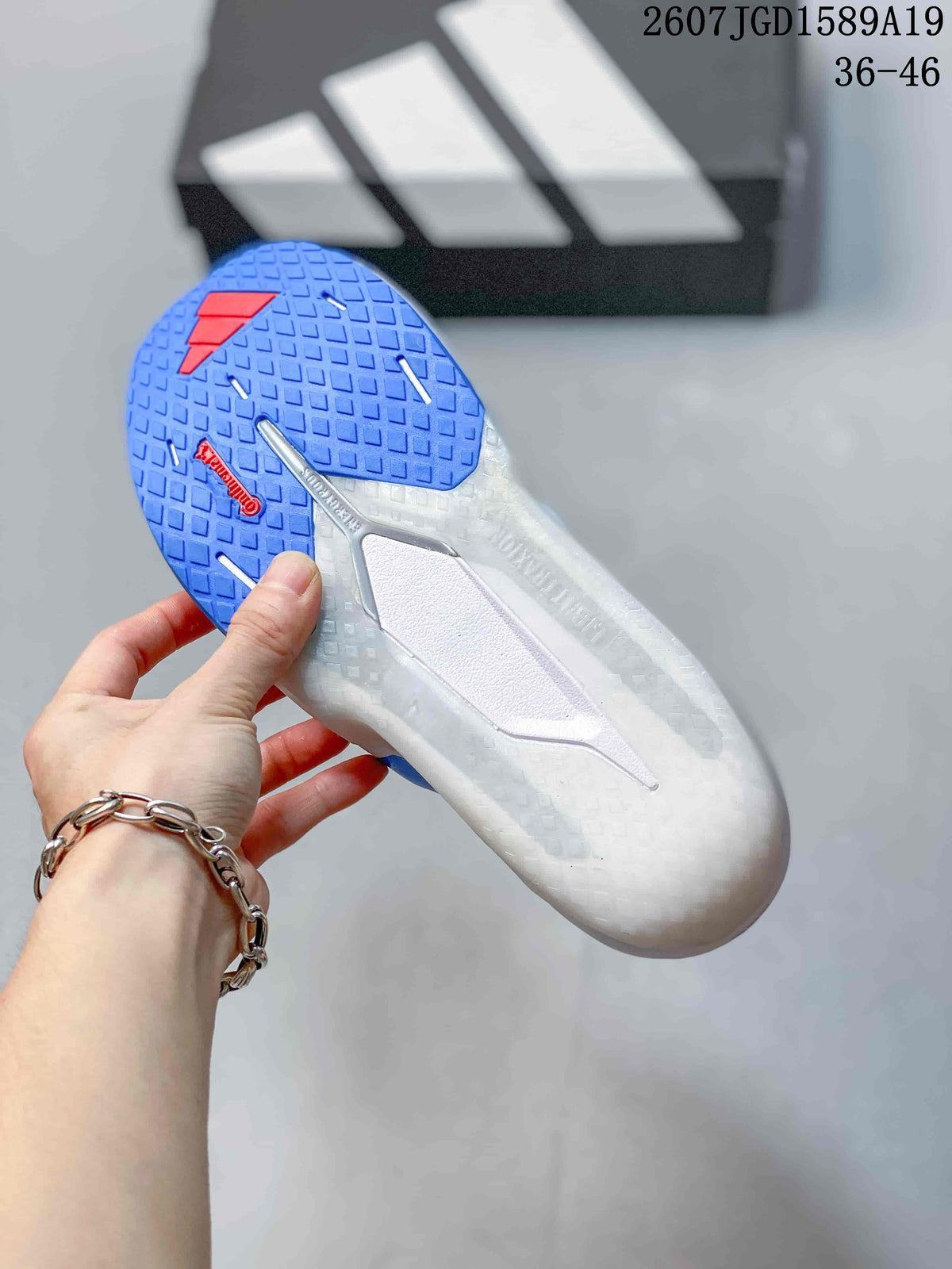 Underside view of the sneaker showing a blue textured outsole, red outsole detail, and central support structure.