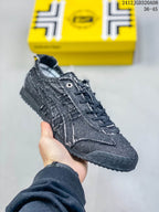 Angled side view of the dark blue low-top sneaker with layered stitched panels and rubber outsole.