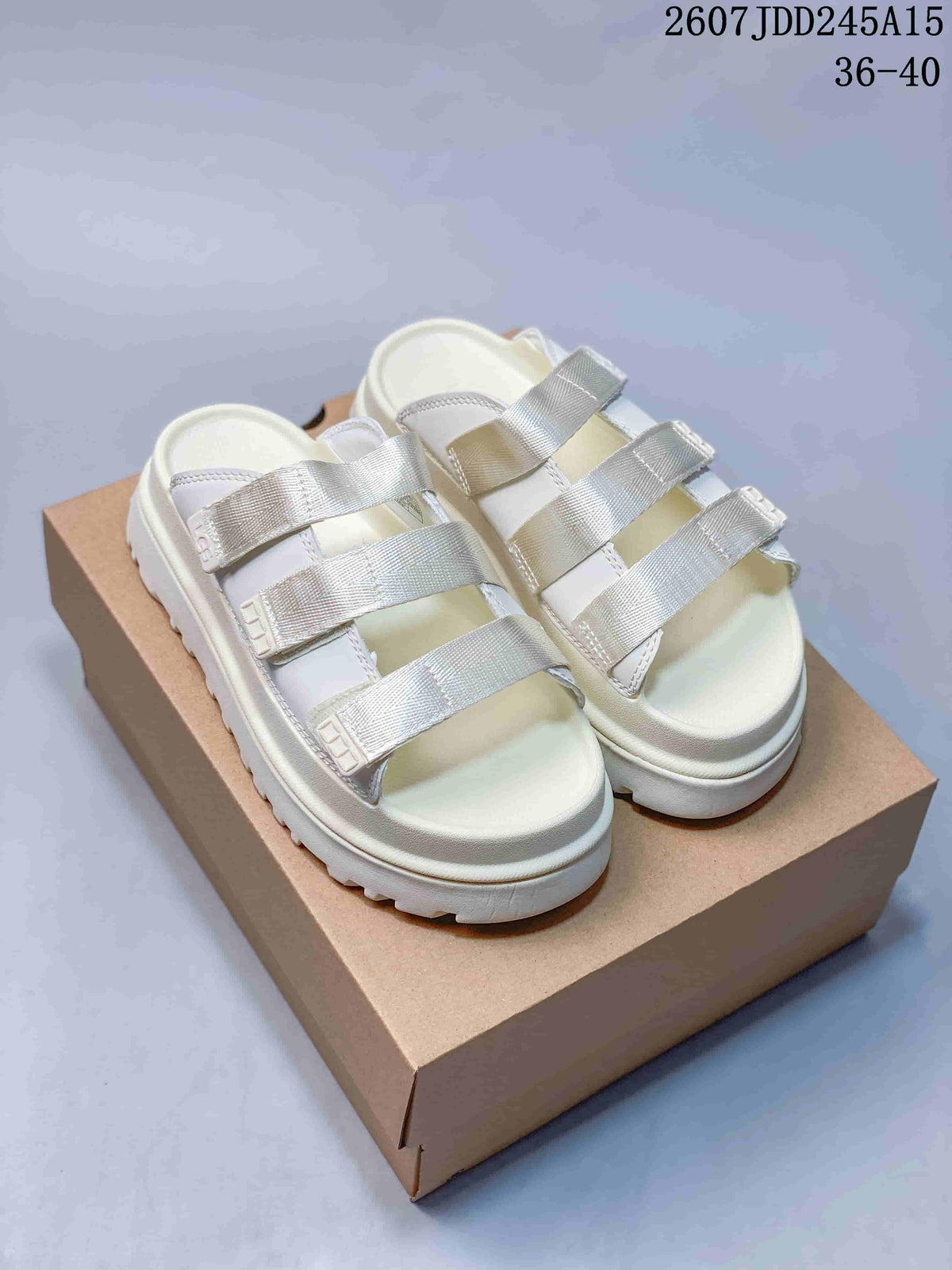 White UGG GoldenGlow slide sandals with three silver-toned adjustable straps on a box.
