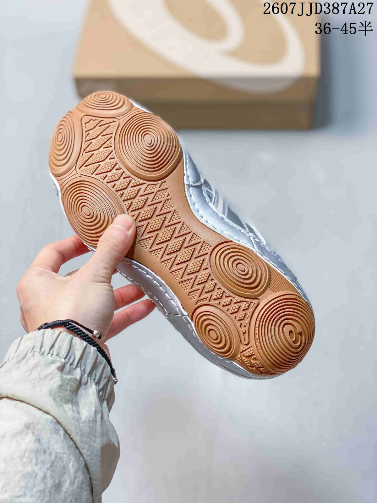 Underside of a silver sneaker showing the gum-colored outsole and circular traction patterns.