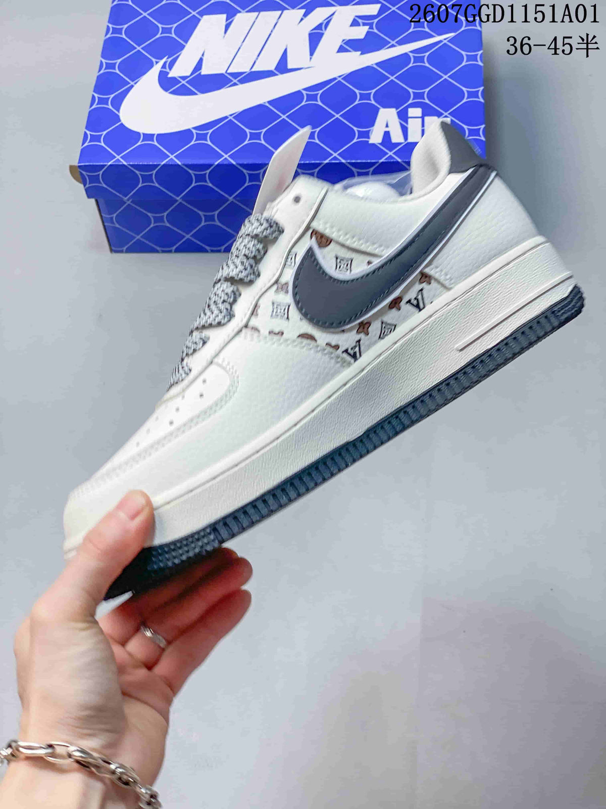 Side profile of a white sneaker with a dark gray Swoosh, monogram-style print, and patterned laces.