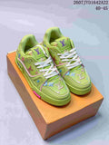 Pair of green Louis Vuitton Trainer low-top sneakers displayed on an orange shoe box, with white laces, multicolor motifs, and pink accents.