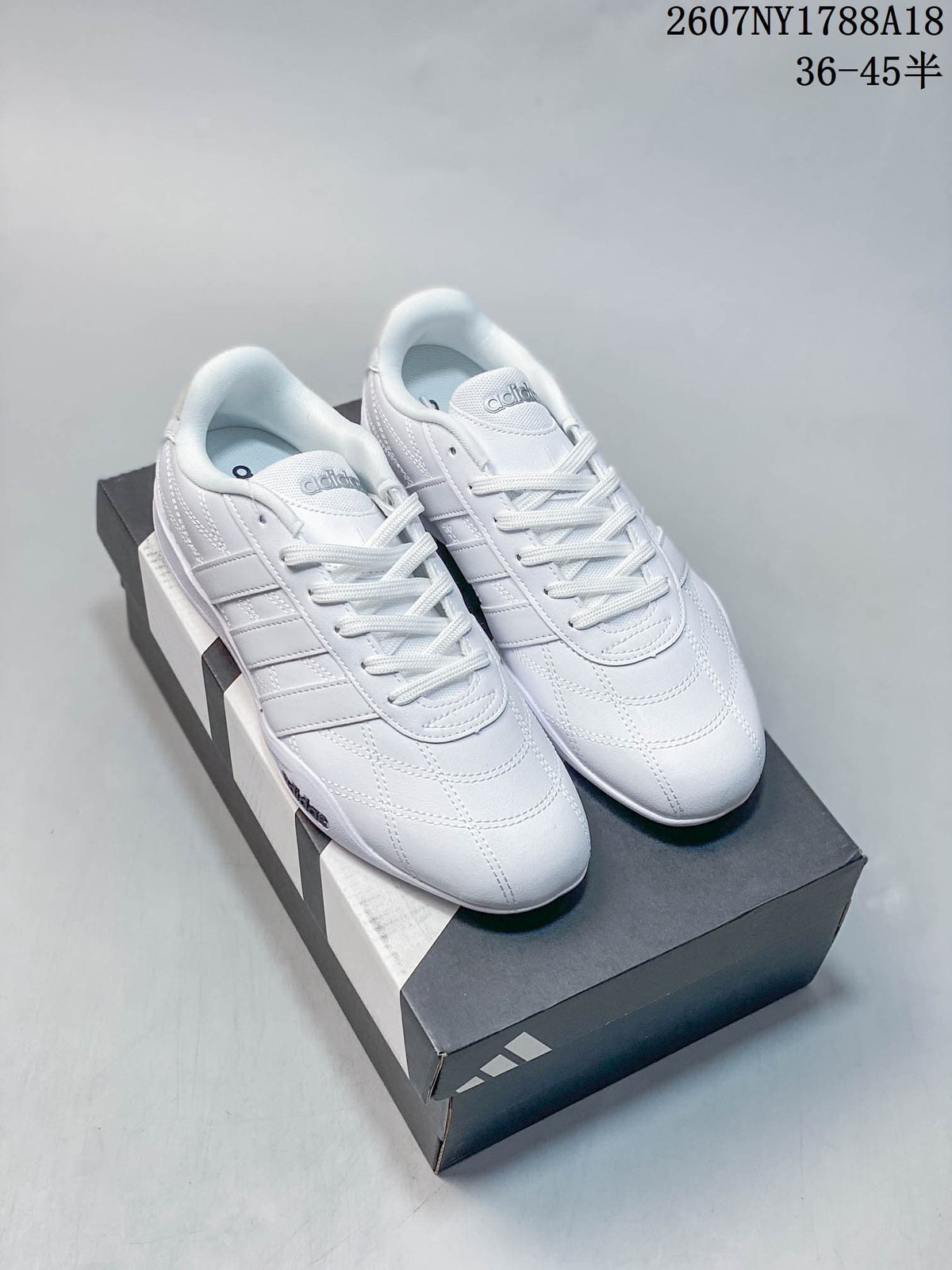 White adidas Adipista trainers with tonal detailing displayed on a shoebox.
