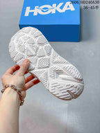 Underside view of the white running shoe showing its patterned outsole