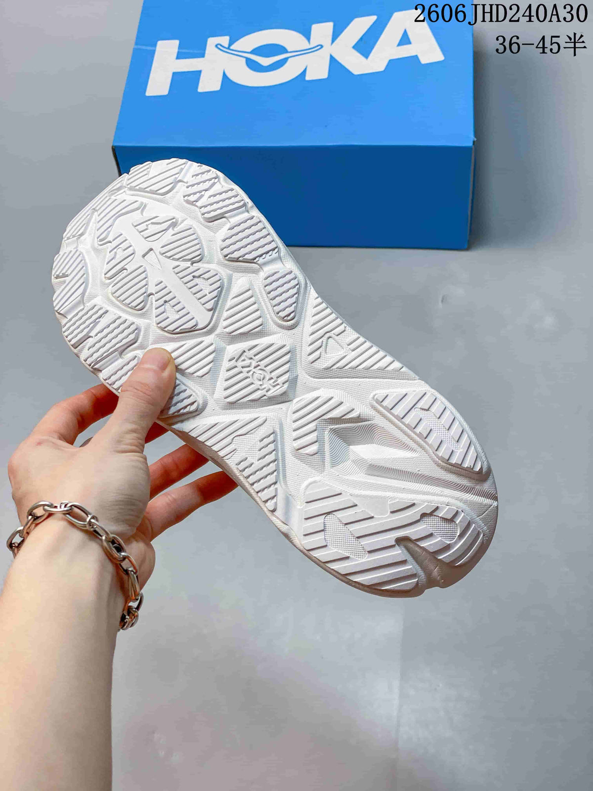 Underside view of the white running shoe showing its patterned outsole