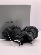 Top-side view of the black sneakers displaying the overlapping lace arrangement and textured upper.