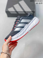 Side view of the sneaker showing the dark upper, white side stripes, white midsole, and red outsole accents.