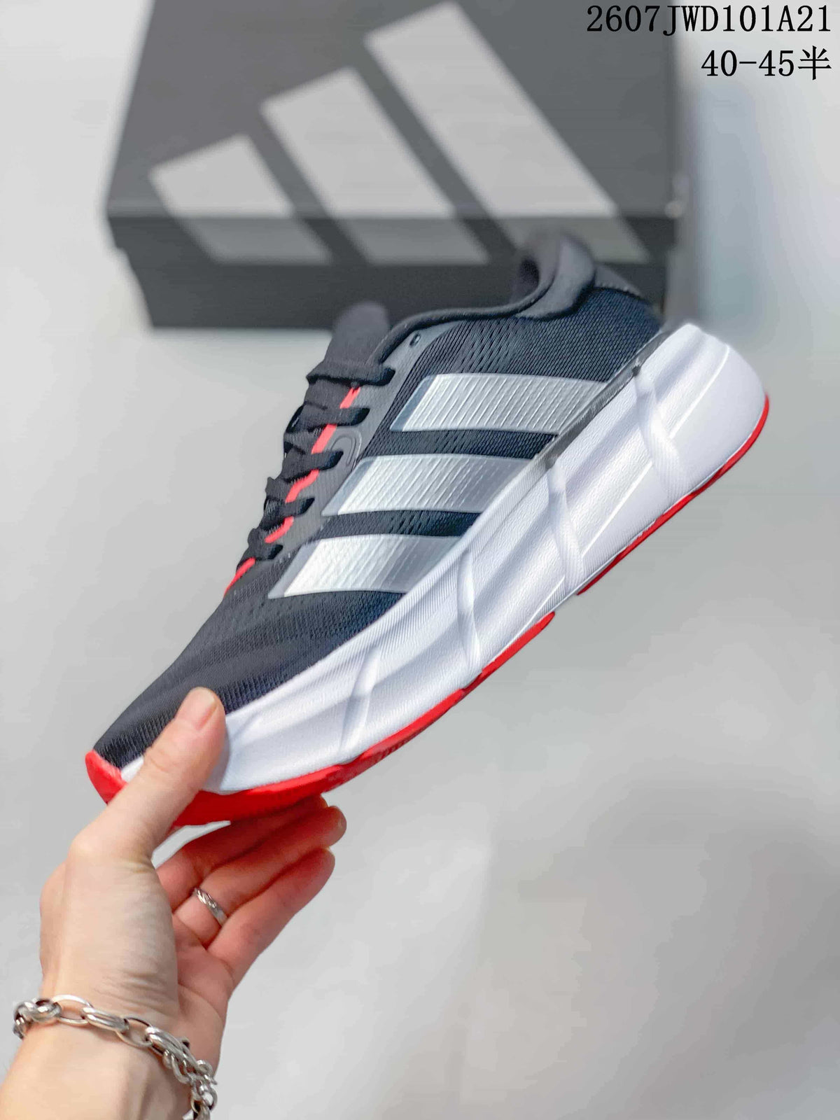 Side view of the sneaker showing the dark upper, white side stripes, white midsole, and red outsole accents.