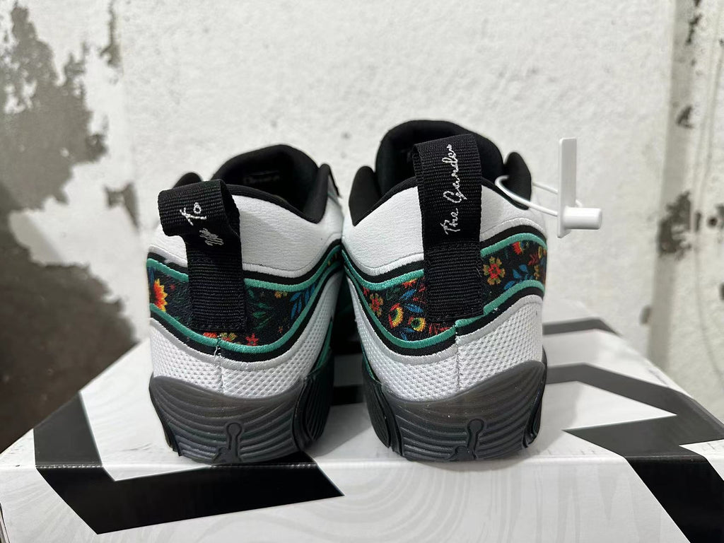 Rear view of black, white, and green Jordan basketball shoes with floral-patterned heel panels.