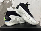 Pair of black and white high-top basketball shoes with neon-green accents, shown from the side.