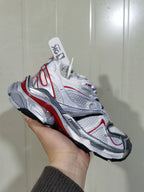 Angled view of the sneaker showing the layered upper, lace fastening, sculpted midsole, and rubber outsole.