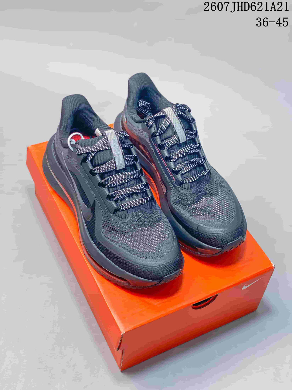 Pair of black and charcoal Nike Air Pegasus Premium sneakers displayed on an orange shoebox, with red midsole accents visible.