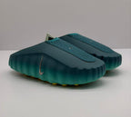 Angled view of the pair of green slides with perforated upper panels and Nike branding.