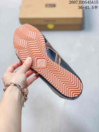 Underside view showing the salmon-colored zigzag outsole and central embossed branding.