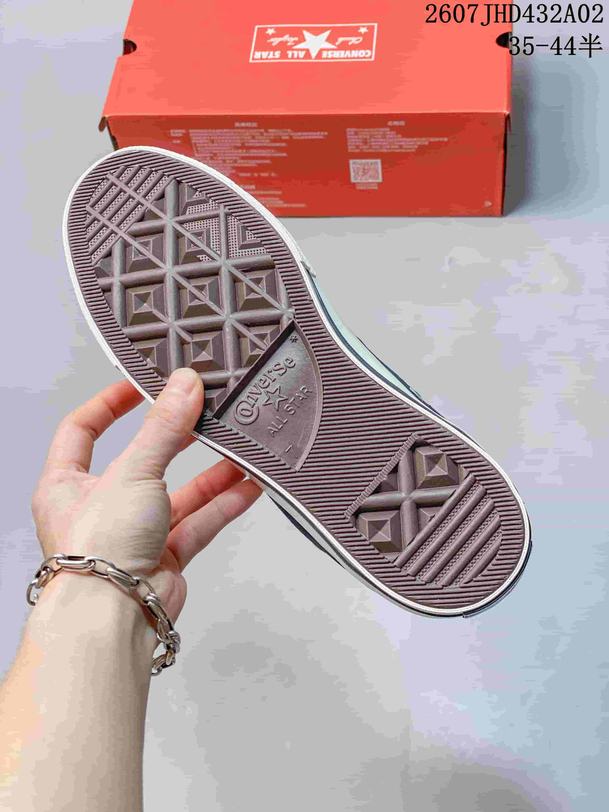 View of the patterned rubber outsole and red shoebox