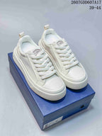 White Dior low-top sneakers with perforated side panels displayed on a blue shoe box; style code 2607GDD607A17 and size range 39–44 are visible above.