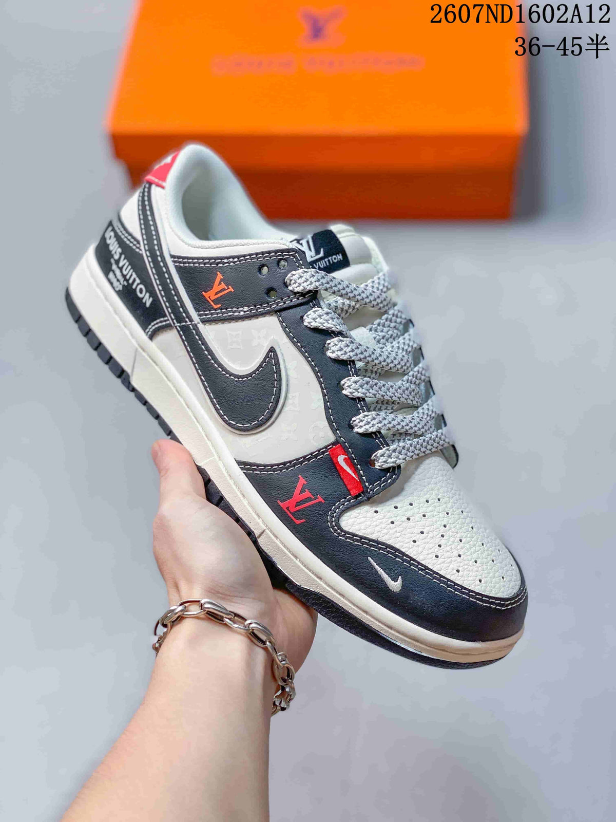 Angled side view of the sneaker showing black and white panels, red accents, patterned laces, visible logo-style markings and a dark rubber outsole.