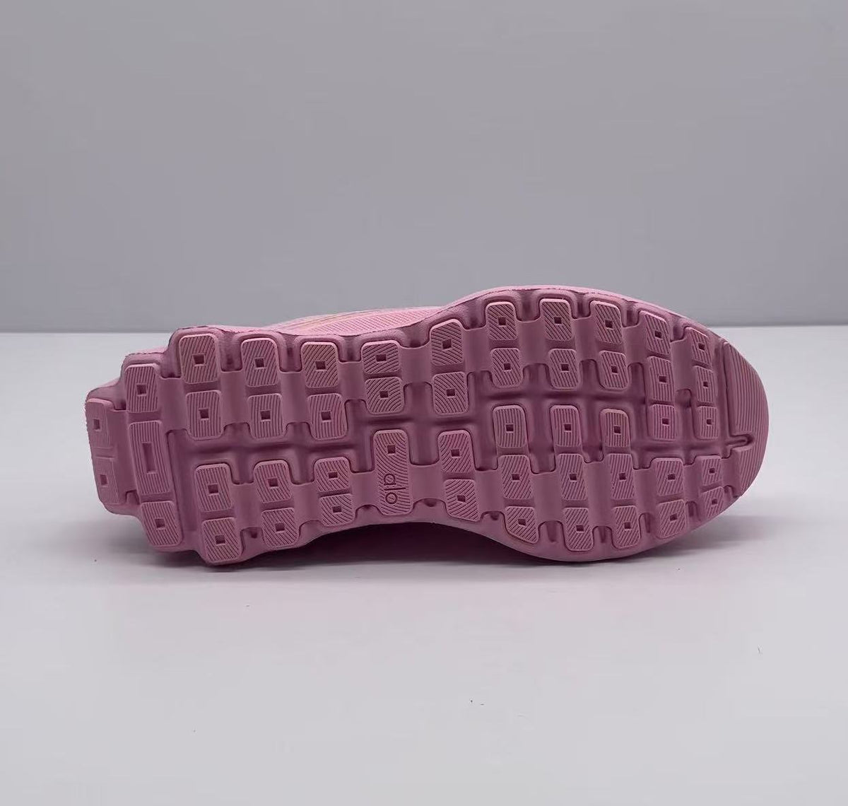 Underside view of the pink sneaker showing the patterned rubber outsole.