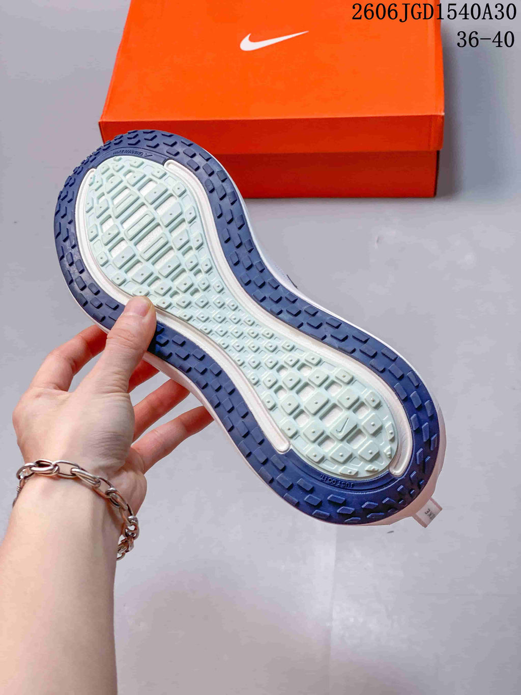 Underside of a Nike Vomero Plus shoe showing a pale center tread and dark blue outsole.