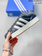 Side view of the black low-top sneaker showing light three-stripe details, a raised white midsole, and gum outsole.