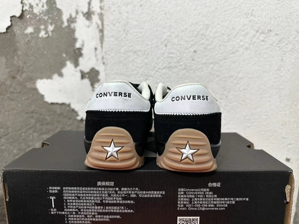 Rear view of black Converse sneakers with white heel panels and gum-colored outsoles.