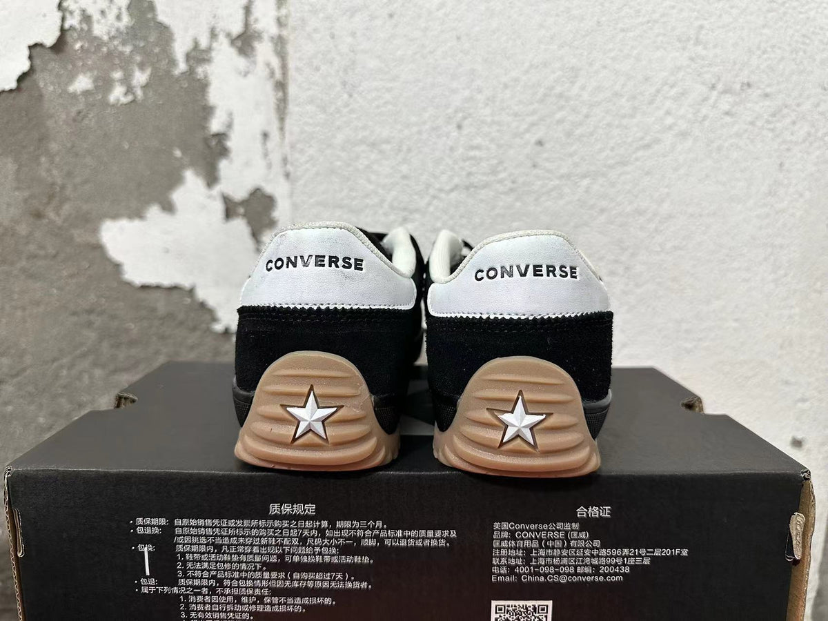 Rear view of black Converse sneakers with white heel panels and gum-colored outsoles.