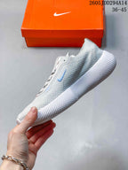 Side view of the light gray Nike sneaker showing the knit upper, blue Swoosh, lace panel, and flexible white sole.