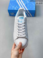 Top view of a white Adidas Stan Smith sneaker with light-blue tongue details and white laces
