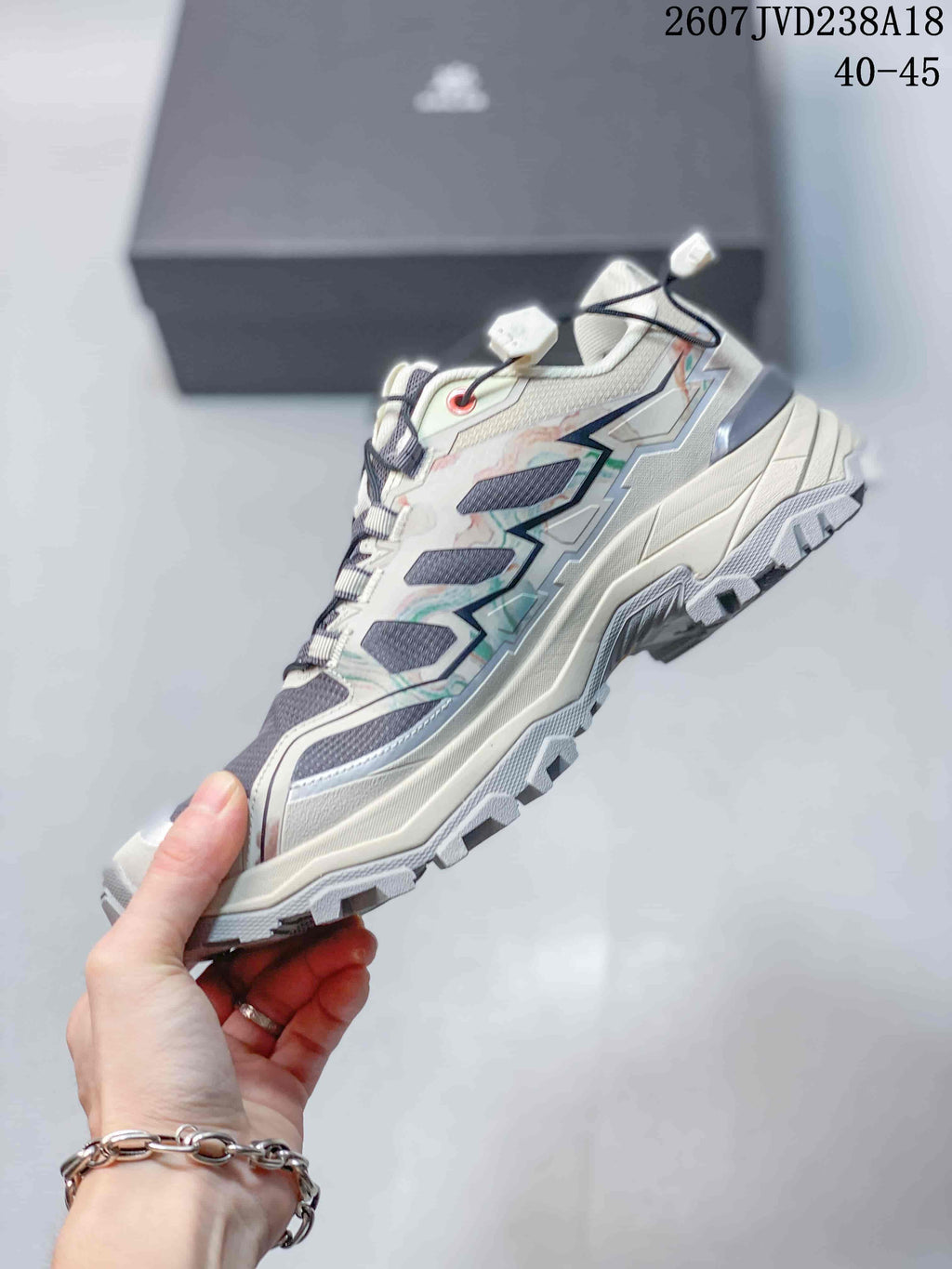 Side view of the low-top hiking shoe showing mesh panels, angular overlays, padded collar, and a thick lugged outsole; size range 40–45 and code 2607JVD238A18 are overlaid.