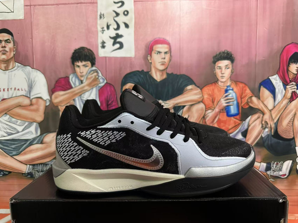Side view of a black and silver sneaker with a Swoosh logo and patterned panel