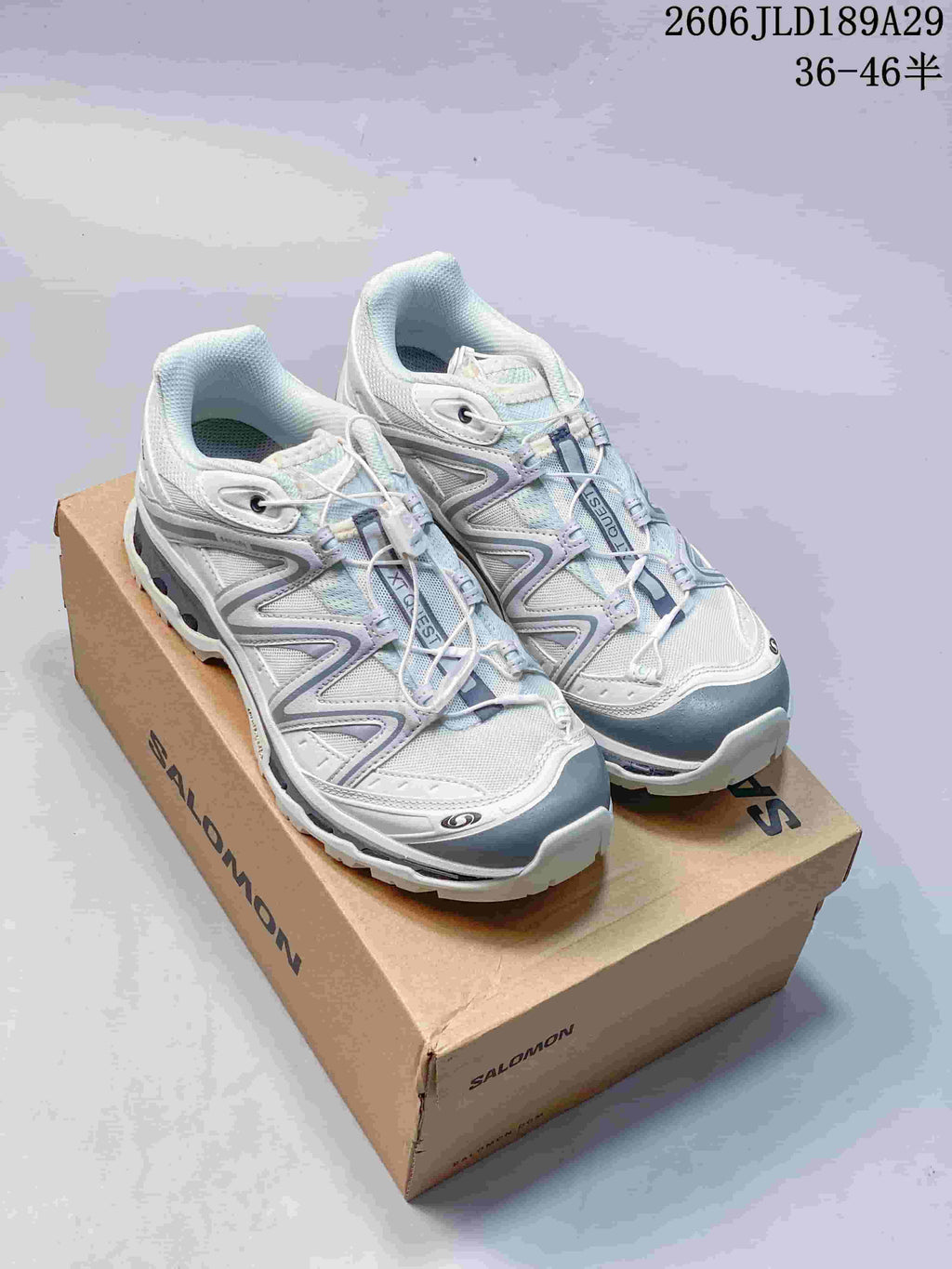 Pair of white and gray Salomon XT-Quest ATHR sneakers on a shoebox.