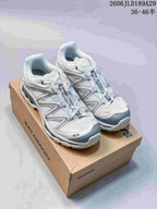 Pair of white and gray Salomon XT-Quest ATHR sneakers on a shoebox.
