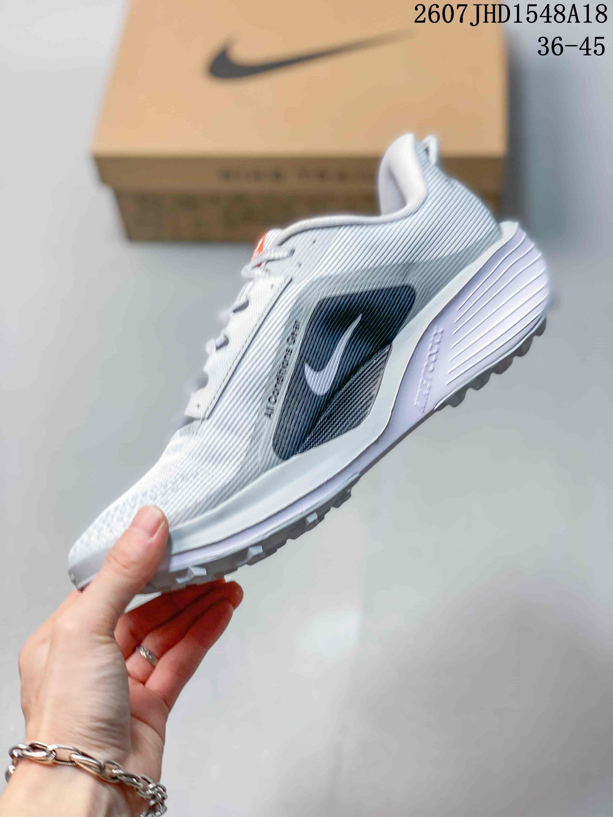 Side profile of the white and gray sneaker showing its layered upper, side branding, raised midsole, and lugged outsole.