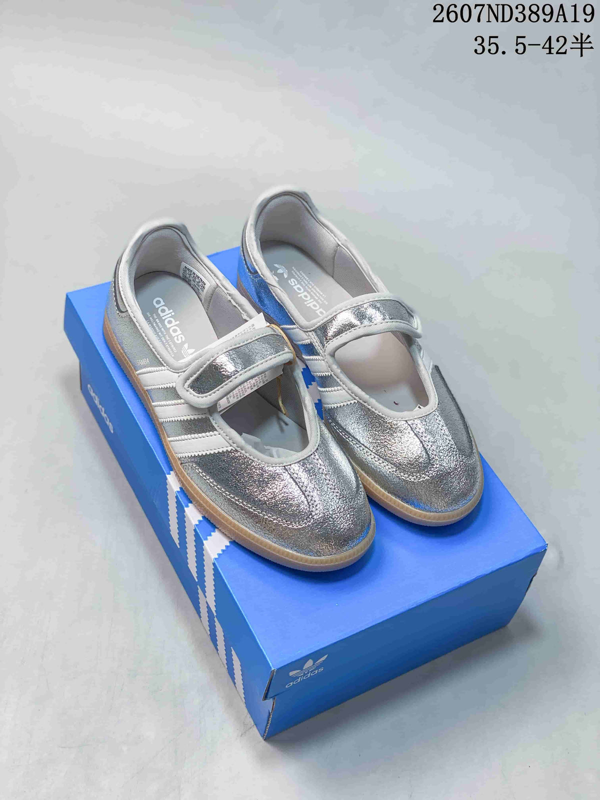 Metallic silver adidas Samba Jane sneakers with adjustable straps displayed on a blue adidas shoebox.