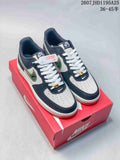 Pair of navy and white low-top sneakers with green camouflage-patterned Swoosh details displayed on a red Nike shoebox.
