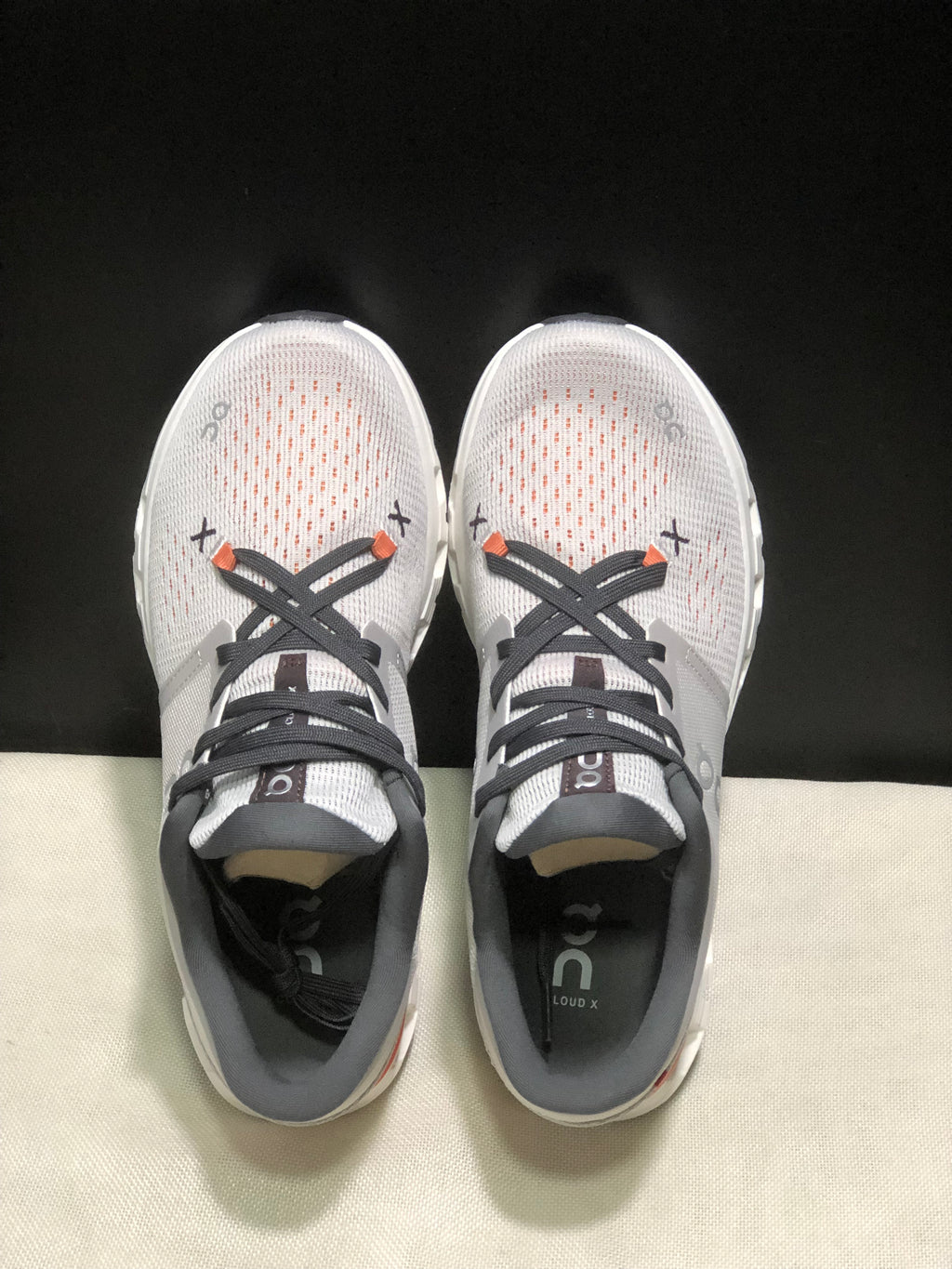 Top-down view showing the textured uppers, dark laces, orange lace details, and insoles marked Cloud X.