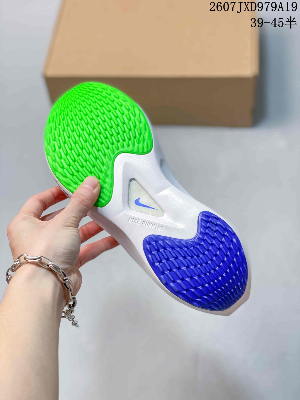 Underside of a Nike running sneaker showing green and blue textured outsole sections and a white midsole.