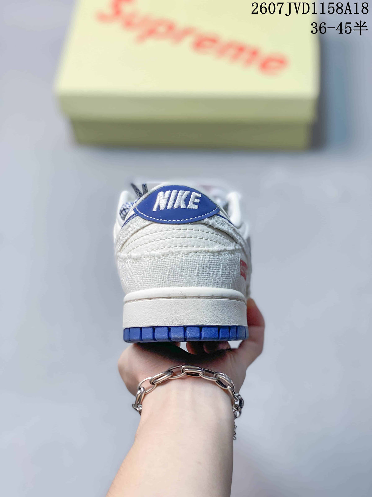 Rear view of the sneaker showing the blue heel label, white upper, and blue outsole edge.