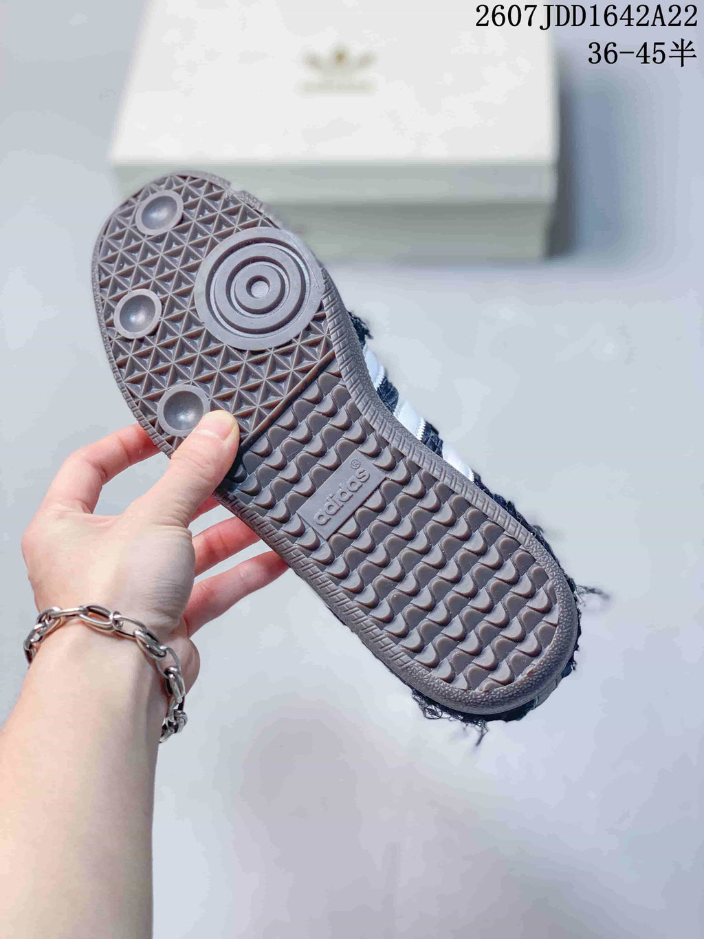 Close view of the patterned gum-colored rubber outsole on a dark Samba OG sneaker.