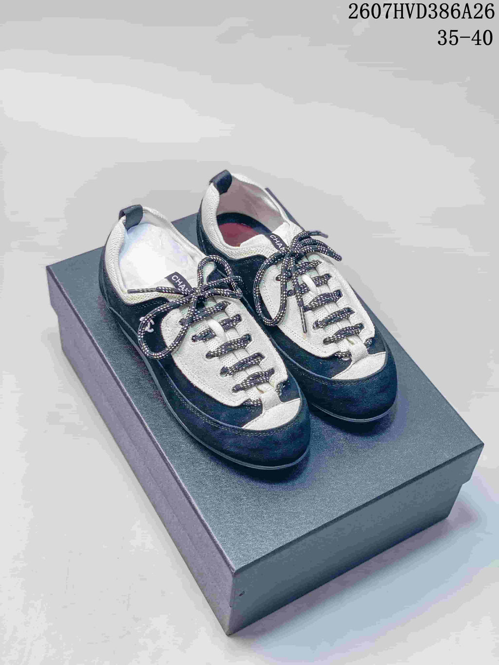 Pair of black and white low-top sneakers displayed on a box, with patterned laces and visible side branding.