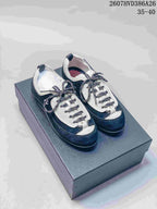 Pair of black and white low-top sneakers displayed on a box, with patterned laces and visible side branding.