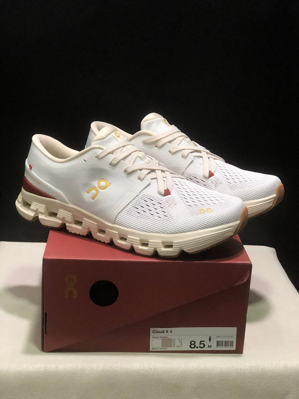 Pair of white On Cloud X4 low-top running shoes displayed on a Cloud X4 shoe box; the box label shows an EU 42 sample size.