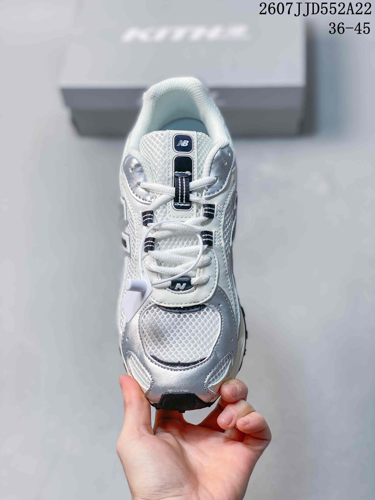 Top view of the sneaker showing the mesh-style toe box, white laces, silver overlays, and tongue branding.