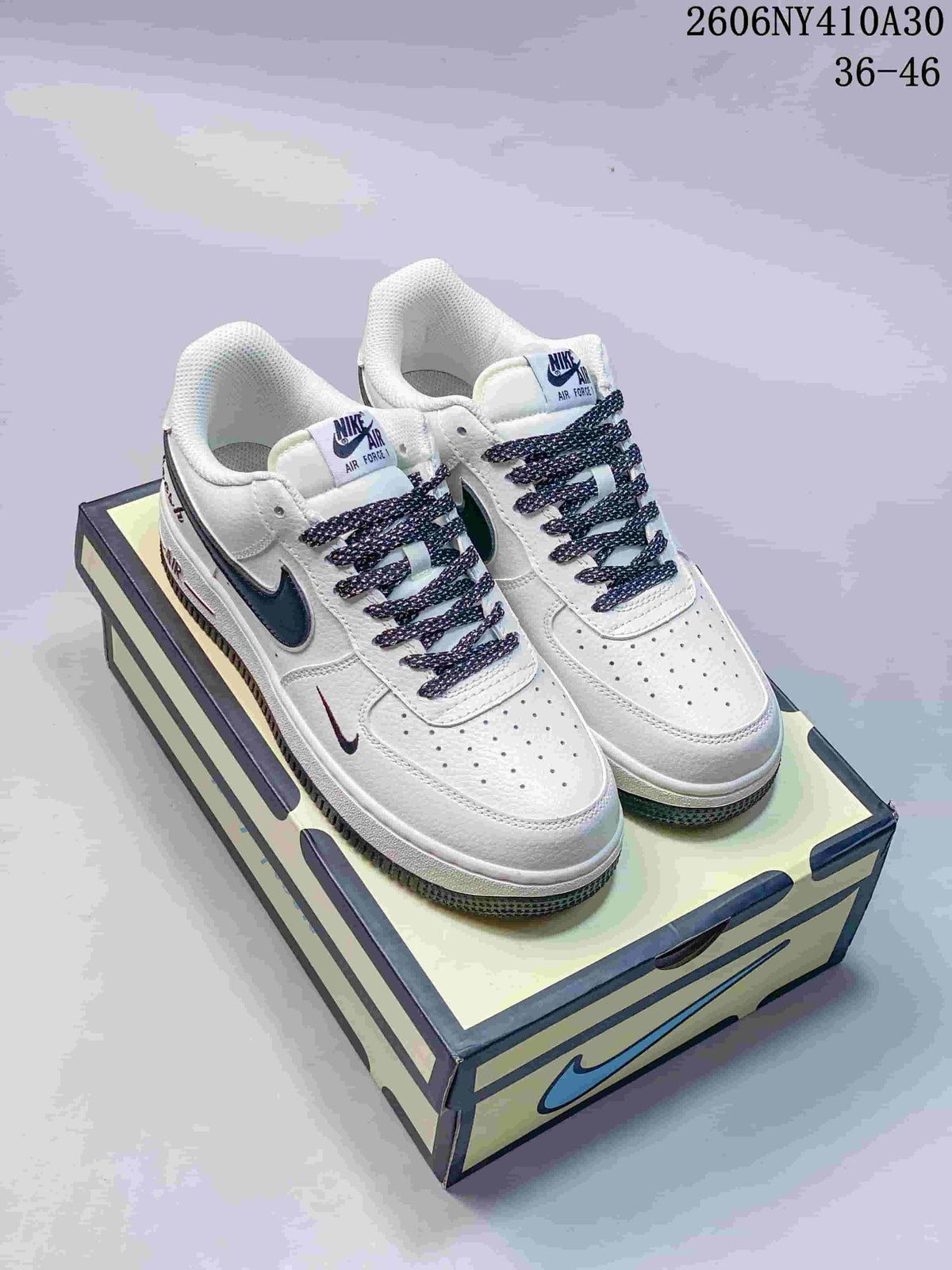 Pair of white and navy Nike Air Force 1 '07 Low sneakers shown on a shoebox