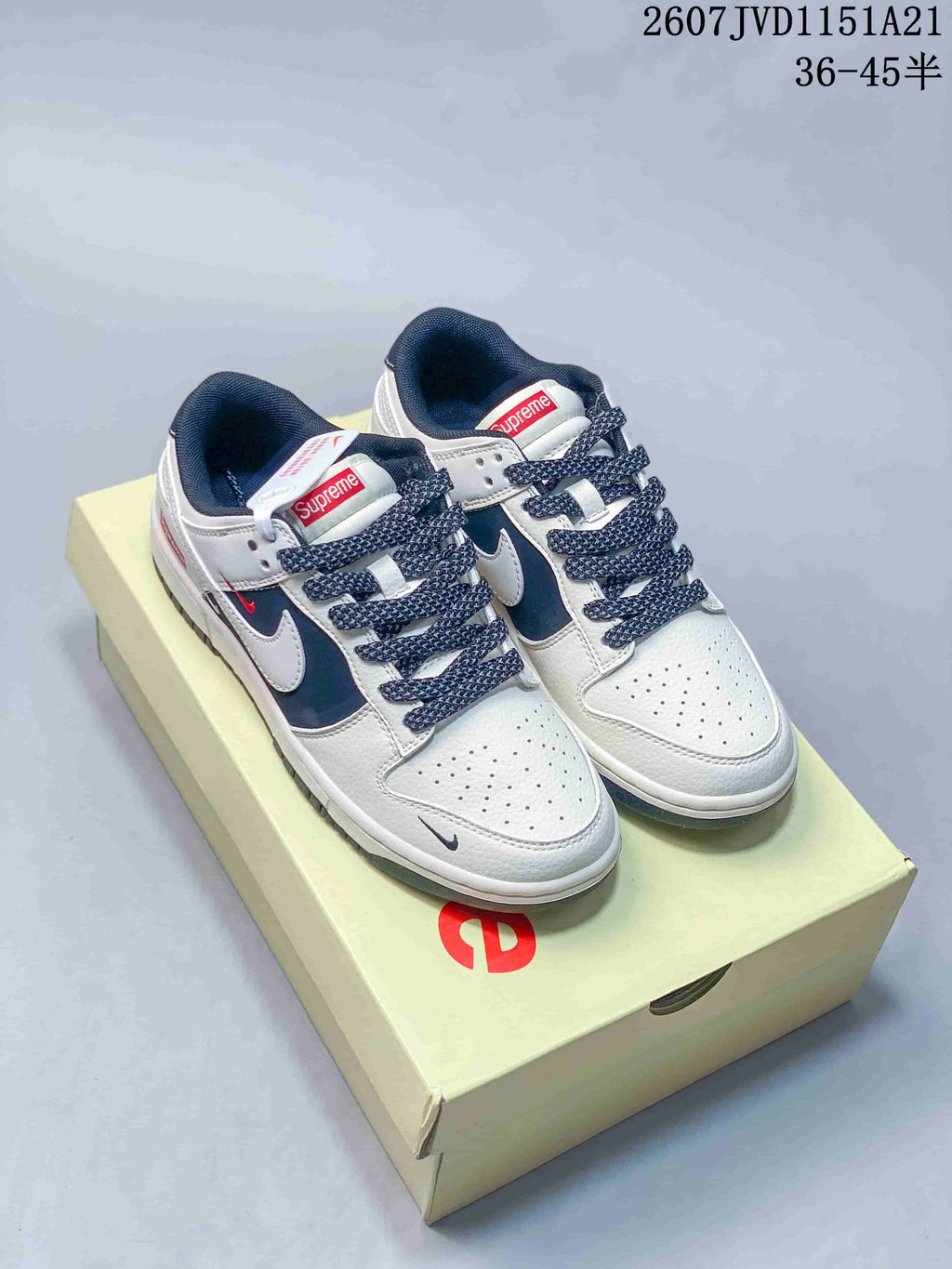 Pair of white, navy and red Nike low-top sneakers displayed on a branded box.